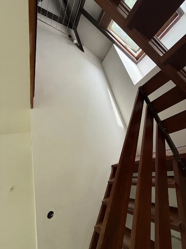Hoge gestucte trapwand met houten trap