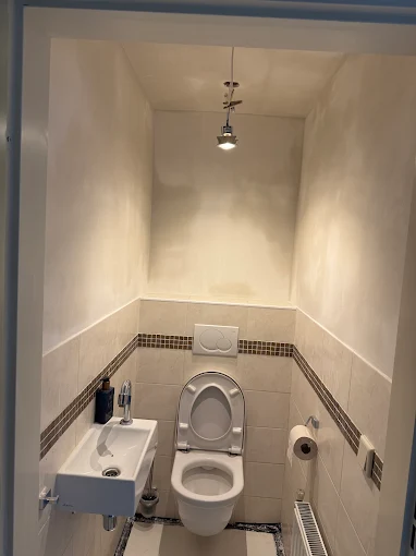 Toiletruimte met glad gestucte wanden boven tegelwerk