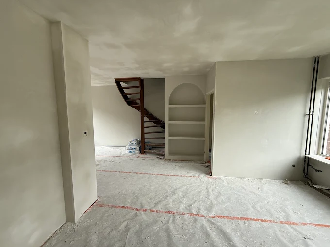Stukadoor werkt een wand af in een modern Nederlands interieur met vers stucwerk